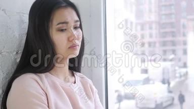 伤心<strong>难过</strong>的年轻亚洲女人坐在窗前